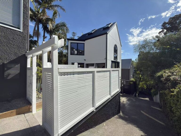 Finished two-storey home on St Georges Bay Road, Parnell, with white vertical cladding and a black standing-seam roof