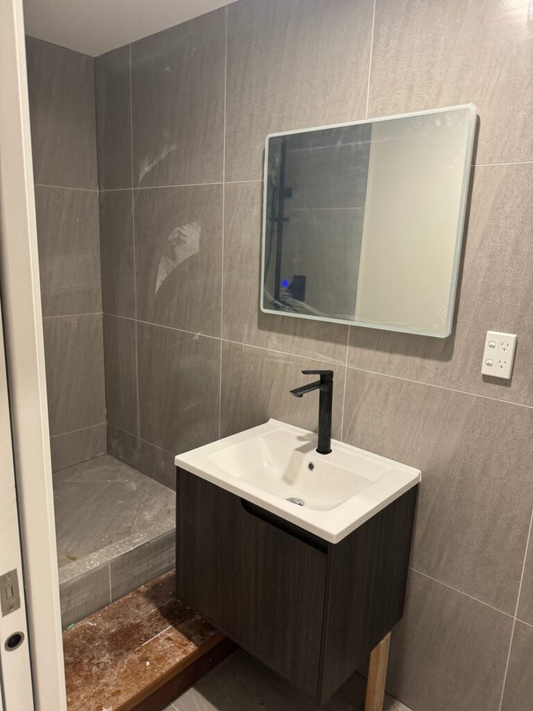 New ground-floor bathroom with tiled walls and black tapware in Forrest Hill